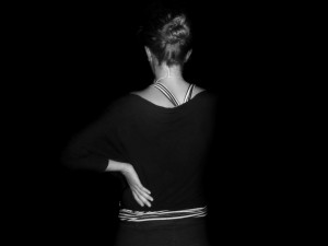 Woman holding back in pain, black and white image