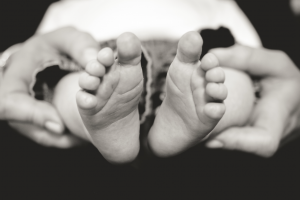 Black and white closeup image of baby's feet in chiropractor's hands