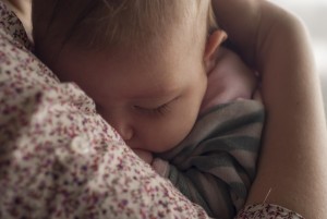 Closeup of baby nestled in mother's arms.