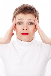 Woman with hands at temples from headache, stressed