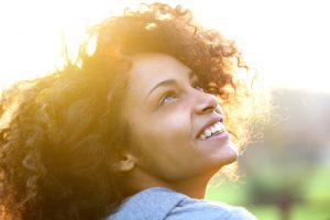 Woman smiling as sun shines from behind her