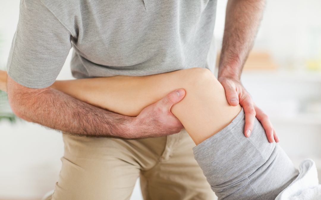 Chiropractor massaging a woman's knee in a room